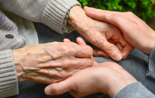 A caregiver offering support to an elderly individual, symbolizing the compassionate care provided to someone living with dementia.